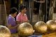 Thailand: Women plastering gold leaf on luk nimit (holy stone spheres), Wat Phrathat Doi Kham, Chiang Mai